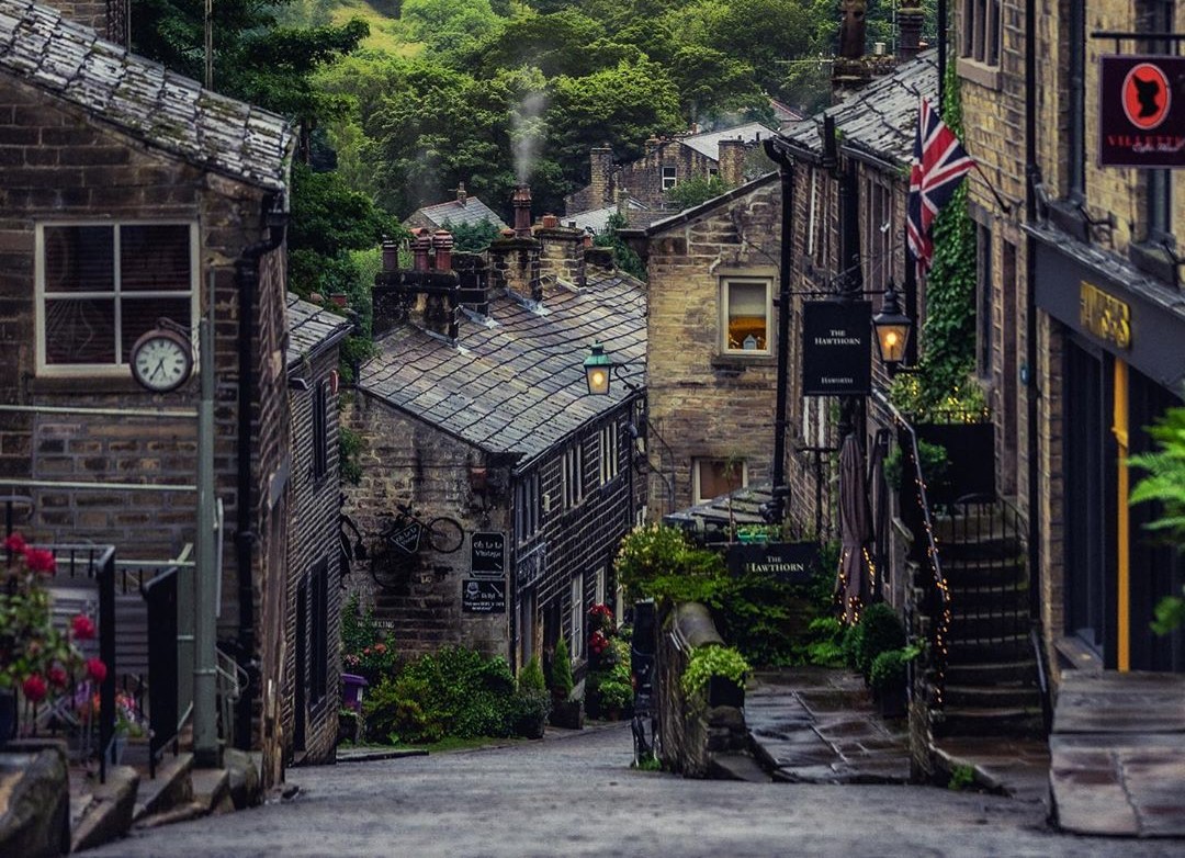 A cobbled village street sloping down towards green Yorkshire hills