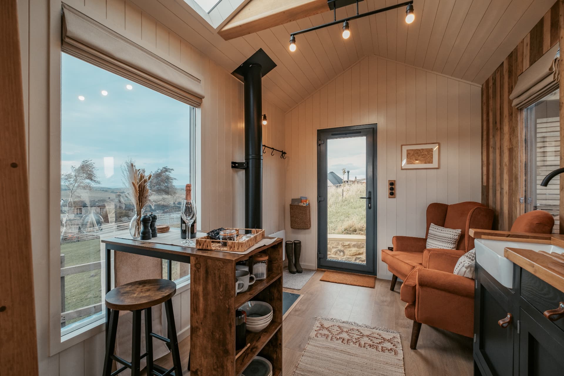 The Bothy at dusk — wine on the table, wood-burning stove and the Dales through the big window