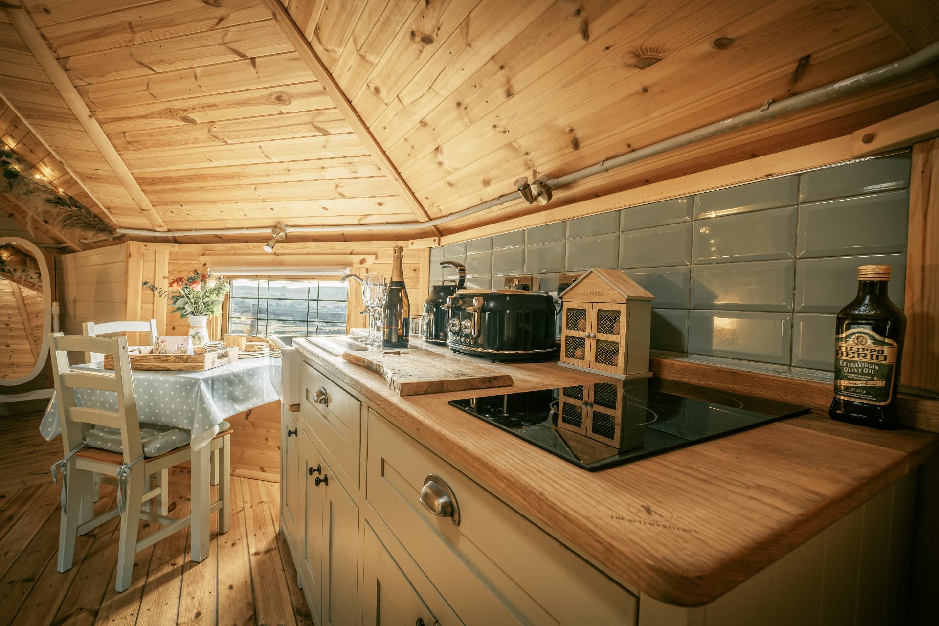 The kitchen inside The Mallard with a bottle of champagne on the counter and the valley through the window