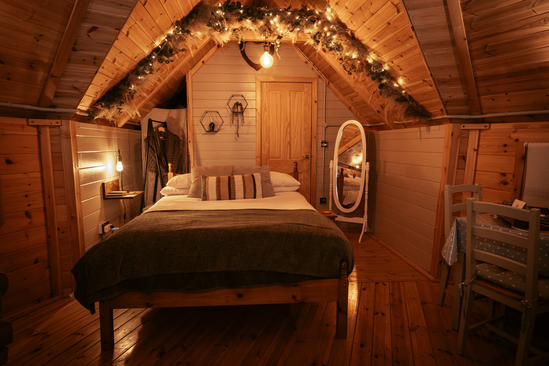 Candlelit bedroom inside The Mallard with fairy lights draped across the beams